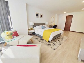 Una habitación de hotel moderna con una cama, mesitas de noche, un escritorio y una silla.