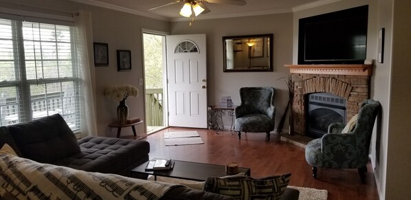 A living room with a fireplace, a television, and a door leading outside.