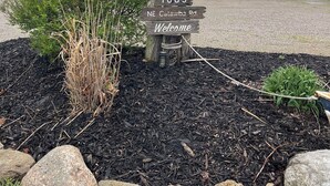 A house with a welcome sign, a mailbox, and a gravel driveway.
