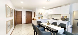 A modern kitchen with white cabinets, a marble countertop, and a dining area with a table and chairs.