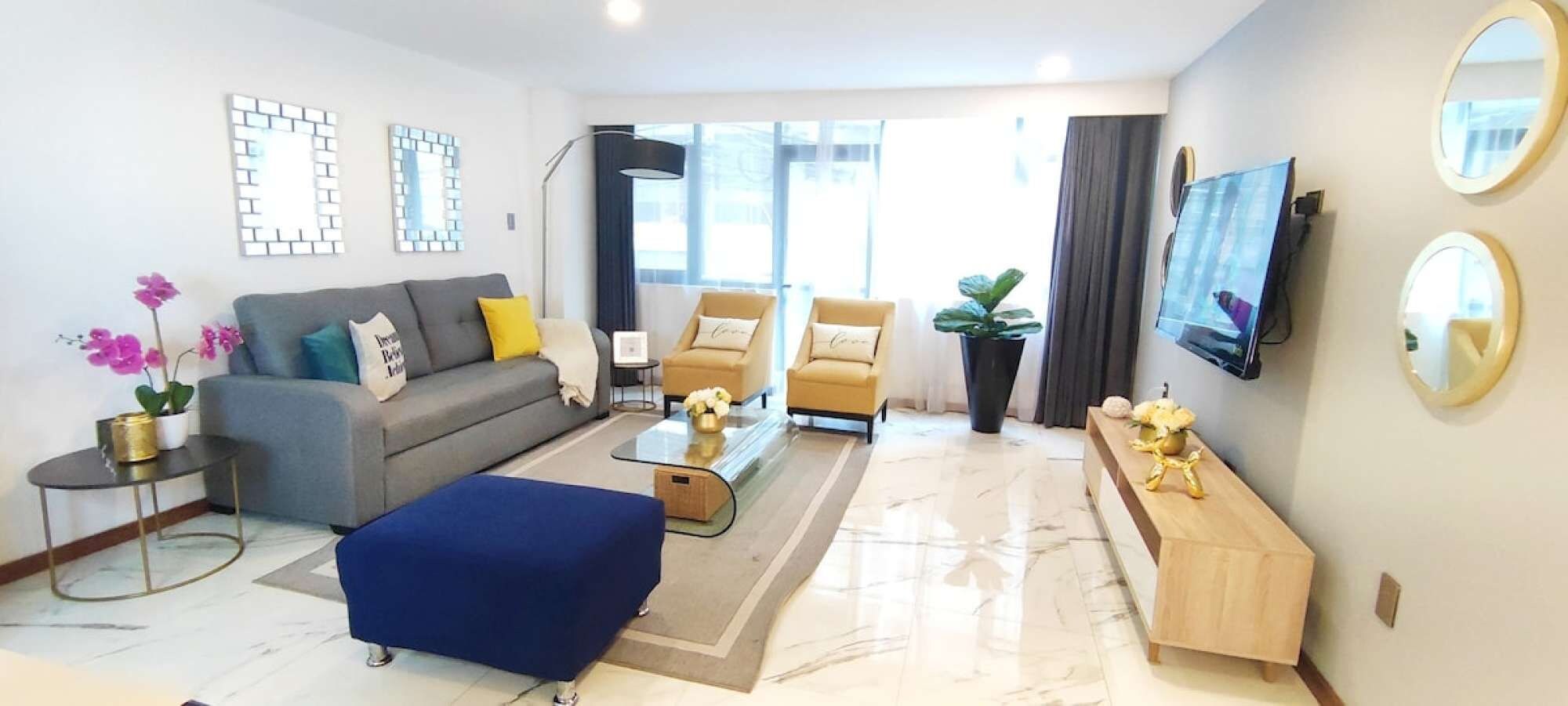 Een moderne woonkamer met een bank, fauteuils, een salontafel en een televisie.