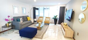 Una sala moderna con un sofá, sillones, una mesa de centro y un televisor.