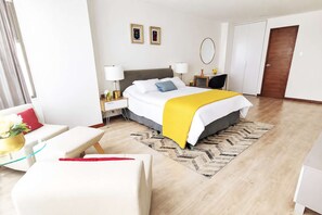 A hotel room with a bed, bedside tables, a chair, a mirror, and a wardrobe.