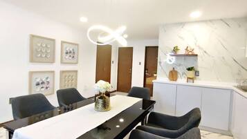 Une cuisine moderne avec un plan de travail en marbre, un coin repas avec une table et des chaises noires, et des tableaux encadrés accrochés au mur.