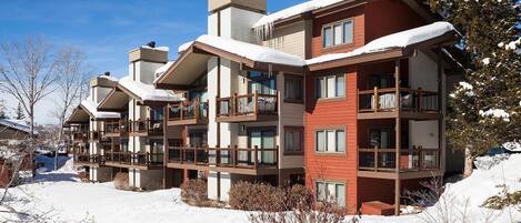 This multi-unit mountain property features spacious balconies and modern alpine architecture set against a pristine winter landscape, perfect for ski season getaways.