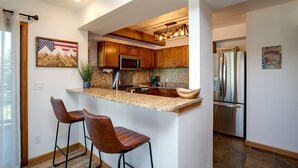 Una cocina moderna con armarios de madera, un refrigerador de acero inoxidable y una encimera de granito.