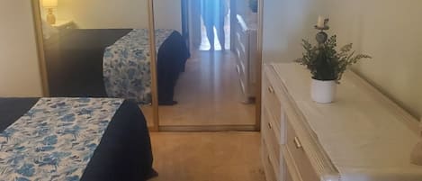 Una habitación de hotel con una cama, un aparador, un espejo y una planta en maceta.