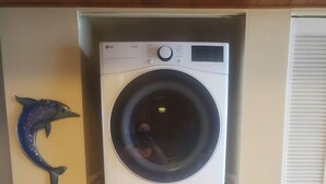Una lavadora y secadora apiladas en un cuarto de lavado con una decoración de delfín en la pared.