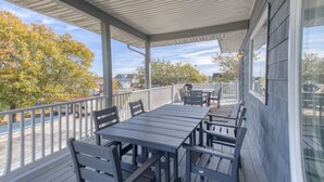 A covered outdoor deck with a table and chairs, overlooking a residential area with autumn trees.