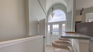 A kitchen with a white countertop, a hanging light fixture, and a view of the outside. - Captain's Quarters (Frederica)
