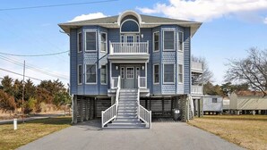 A two-story house with a front porch, a staircase leading to the entrance, and a garage attached to the right side. - Captain's Quarters (Frederica)