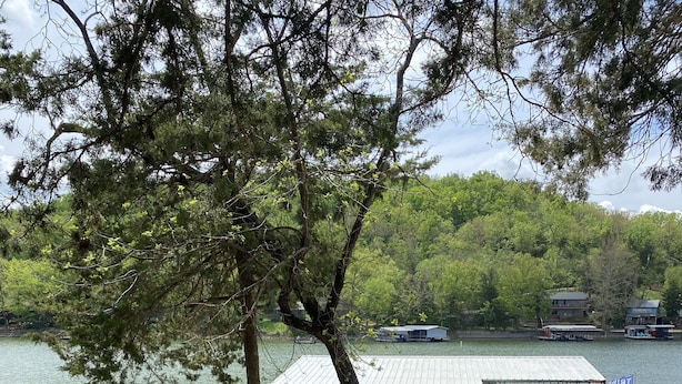 A lakeside deck with a dock, a covered seating area, and an American flag.
