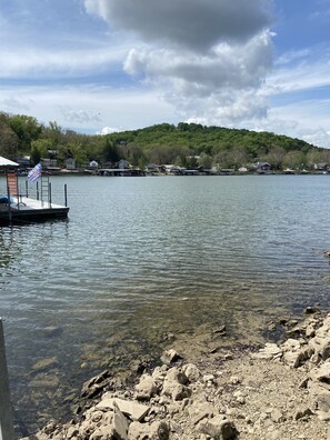 Un lac avec un quai et un drapeau, entouré de maisons et d’arbres.