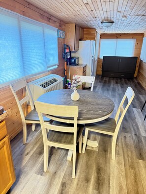 Une cuisine compacte avec des meubles de rangement en bois, une table à manger avec des chaises et un petit réfrigérateur.