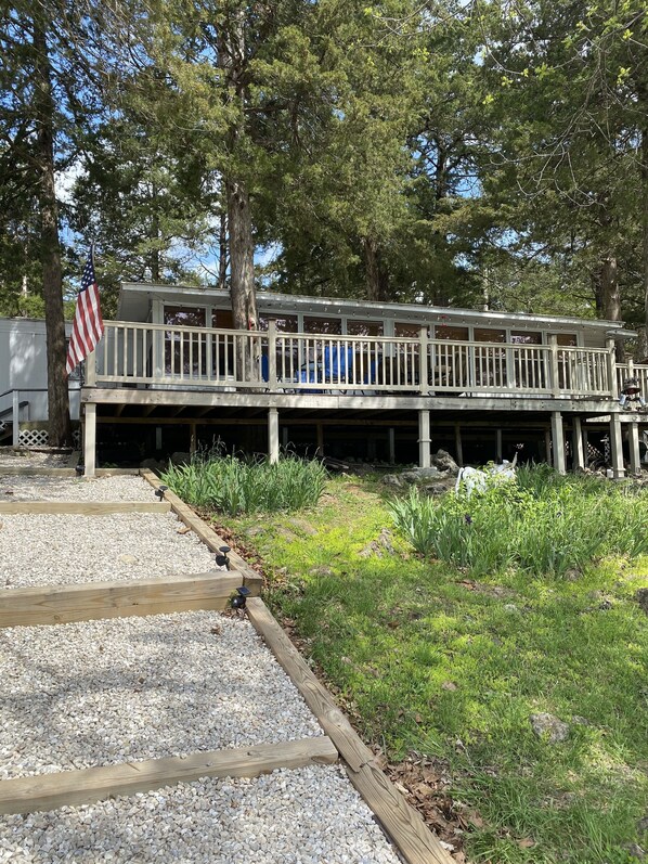Une terrasse en bois avec des rampes, un drapeau américain et un bâtiment doté d’une zone abritée.