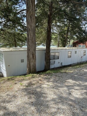 Une rangée de camping-cars blancs est stationnée dans un terrain de camping, avec des arbres en arrière-plan.