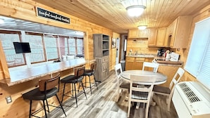 A wooden interior with a bar area, dining table, and kitchen.