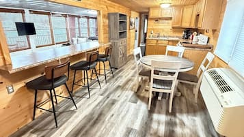 A wooden interior with a bar area, dining table, and kitchen.