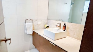 Une salle de bain moderne avec un lavabo blanc, un grand miroir et un porte-serviettes.