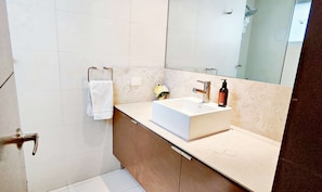 Une salle de bain moderne avec un lavabo blanc, un grand miroir et un porte-serviettes.