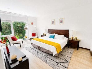 A modern bedroom with a large bed, bedside tables, a desk, and a window with a view of greenery. - Tamayo · Hot tub and terrace near Masaryk · 2 baths (Ciudad de México)