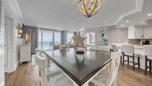 A spacious dining area with a dark wooden table, white chairs, and a decorative starfish centerpiece.