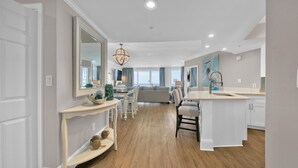 A spacious living area with a large sofa, a dining table, and a kitchen island.