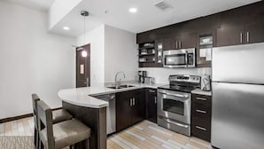 A modern kitchen with dark cabinets, stainless steel appliances, and a bar area with seating. - Hilton Oceanaire Resort Escape – Oceanfront Bliss with Dual Oceanview Balconies! (Virginia Beach)