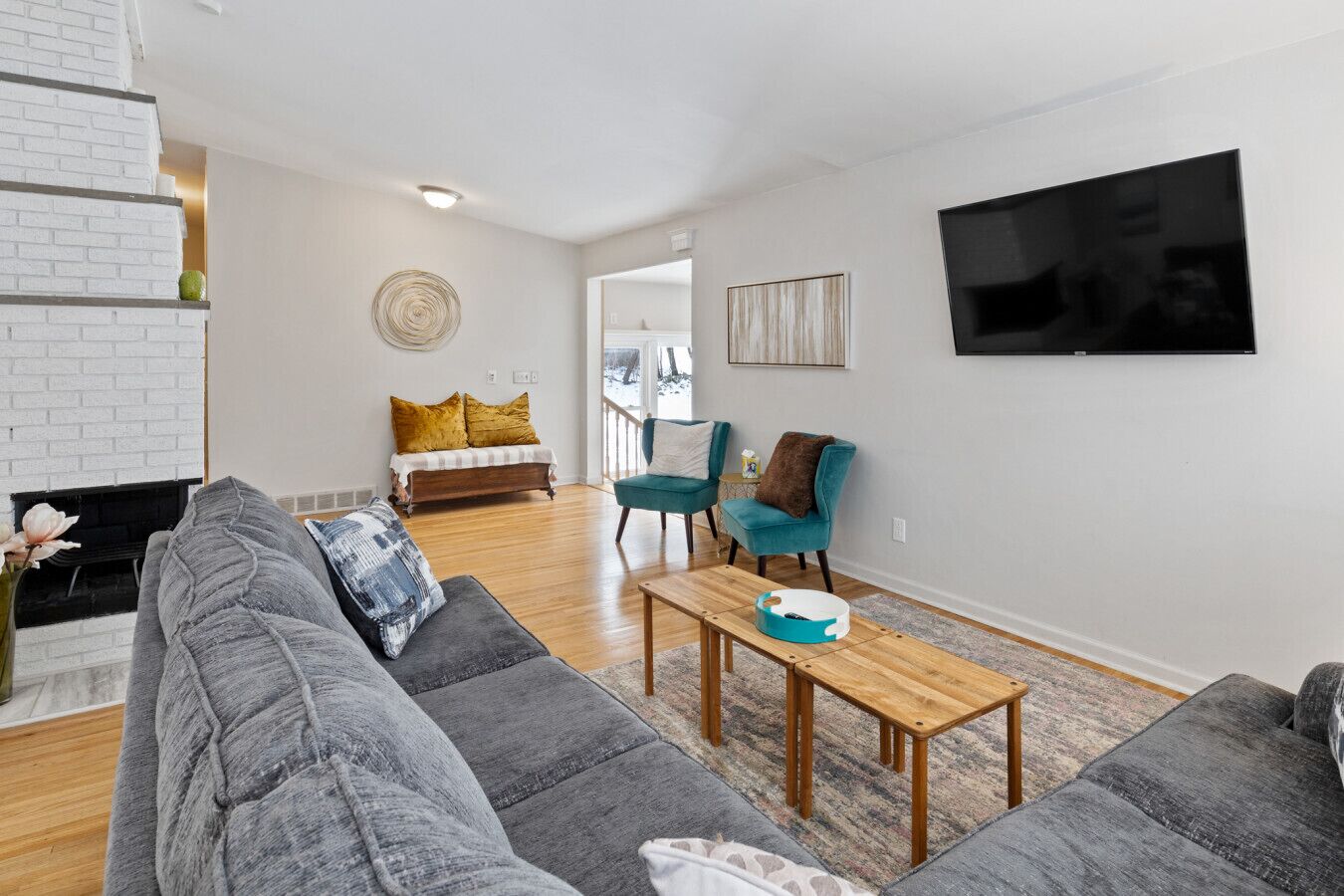 A modern living room with a fireplace, sofa, chairs, and a flat-screen TV.