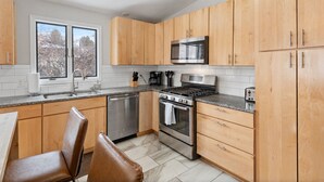 A modern kitchen with wooden cabinets, stainless steel appliances, and a granite countertop. - Bright "Mid-Century Modern" Ranch (Rochester)