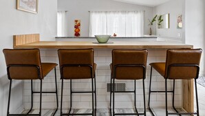 A kitchen with a central island, four bar stools, and a window with curtains. - Bright "Mid-Century Modern" Ranch (Rochester)