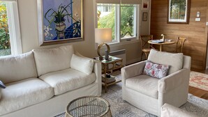 A cozy living room with two sofas, a table, chairs, and artwork on the walls.