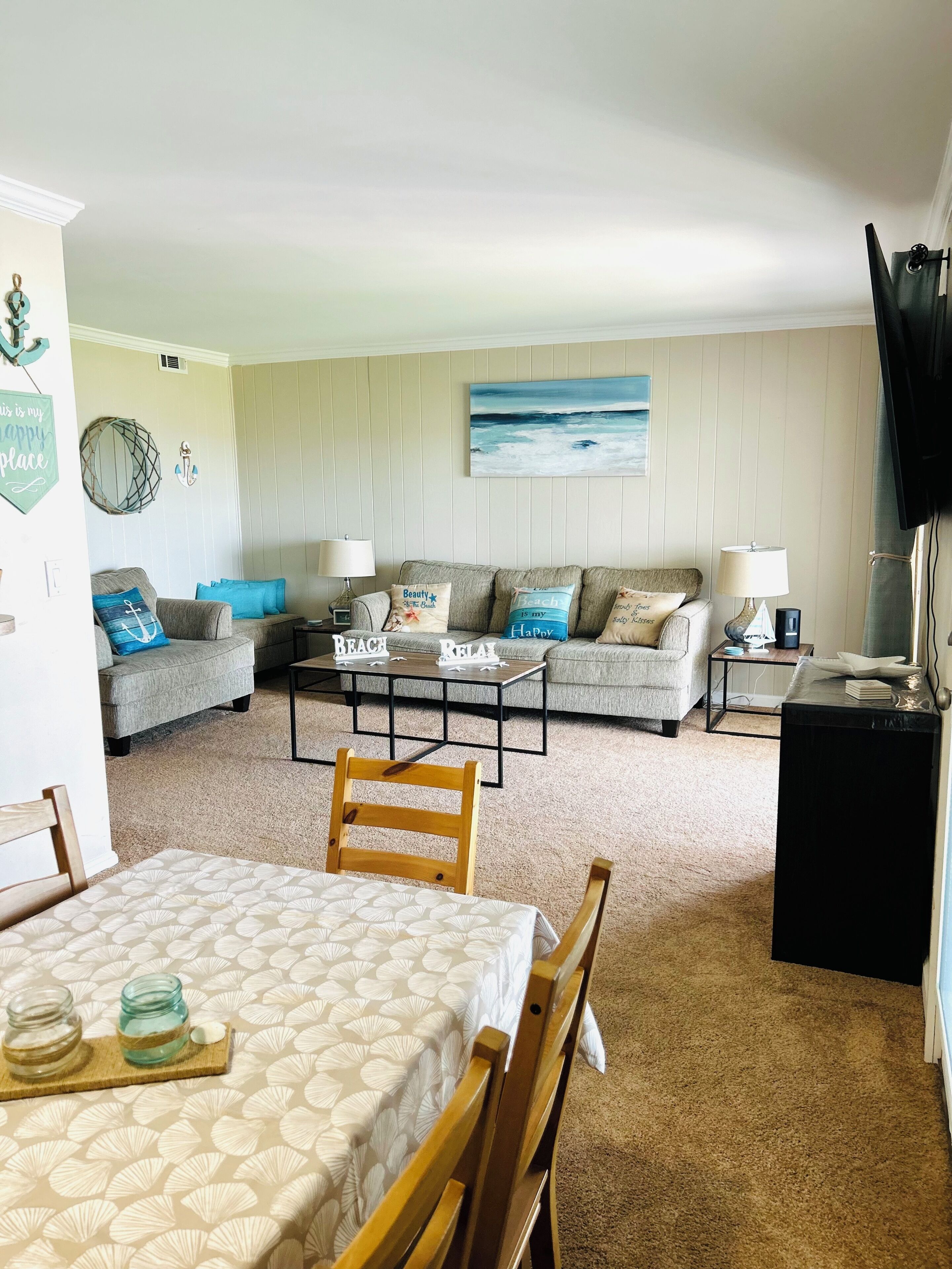 A living room with a sofa, coffee table, and a dining area with chairs and a table.