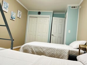 A bedroom with two beds, a ladder, a door, and wall art.