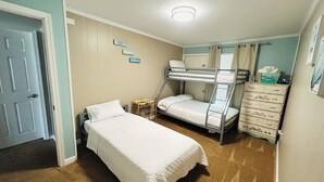 A bedroom with bunk beds, a single bed, a dresser, and a door.