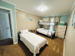 A bedroom with bunk beds, a single bed, a dresser, and a door.
