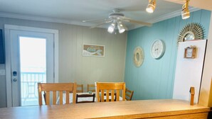 A dining area with wooden chairs and a table, a ceiling fan, and wall decorations.