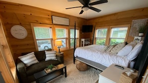 Una camera accogliente in stile chalet, con un letto, un divano, un tavolino e una TV.
