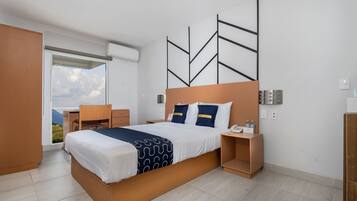 Habitación de hotel moderna con una cama grande, un escritorio y vistas a la montaña a través de la ventana.