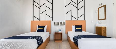 A hotel room with two beds, a small bedside table, a mirror, and a wall-mounted air conditioner.