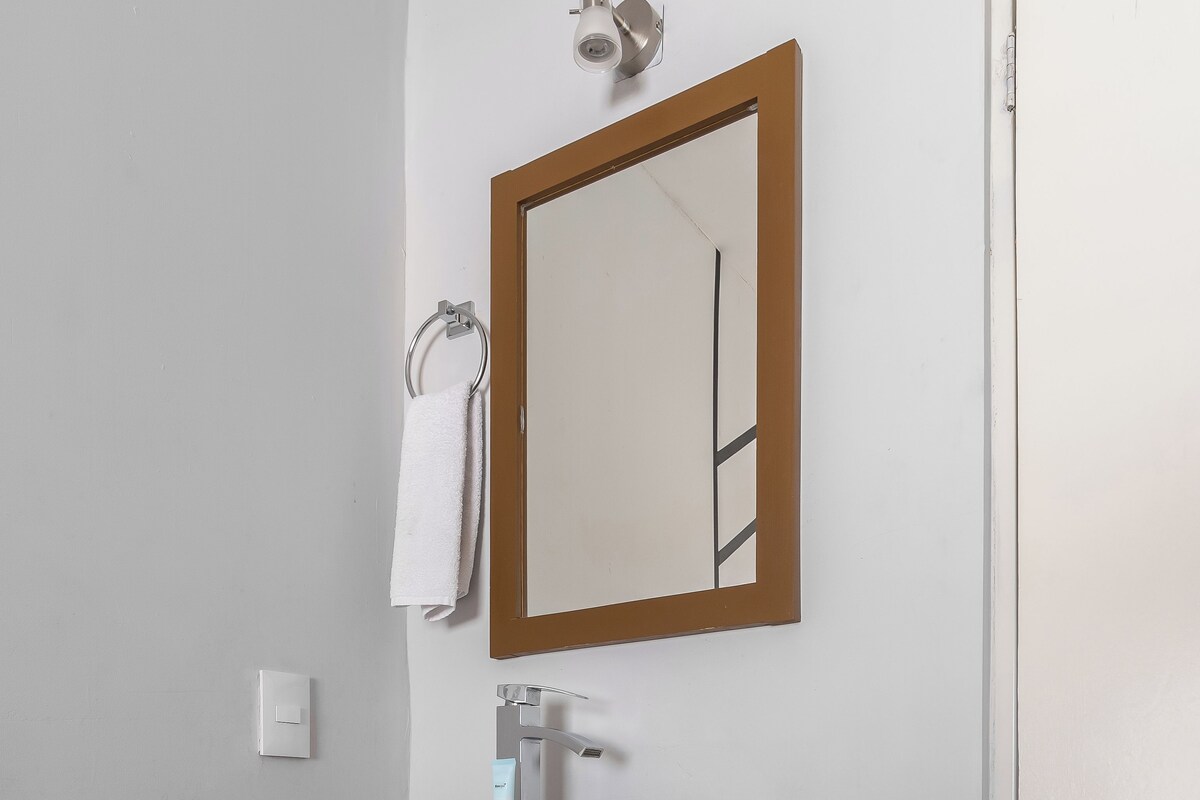 A bathroom with a white sink, wooden vanity, a mirror, and a towel hanging on the wall.