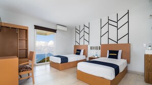 Habitació d'hotel amb dos llits, una taula de treball i una cadira. Hi ha una finestra gran que mostra vistes a les muntanyes.