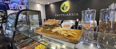 A buffet area with a variety of food options including a sandwich, fries, and fruit.