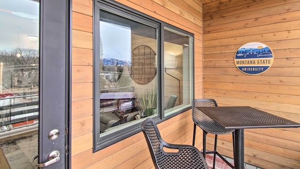Habitación con paneles de madera, una ventana grande, una mesa y dos sillas. Se ve un cartel con la inscripción "Montana State University".