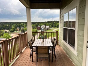 A wooden deck with a table and chairs, overlooking a residential area with houses and trees. - Luxury Ski-In/Out Condo – 305 Soaring Eagle, Stunning Sunrise Views & Hot Tubs! (Snowshoe)
