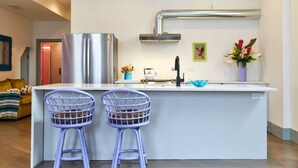 A modern kitchen with a central island, two bar stools, a stainless steel refrigerator, a sink, and a decorative vase. - Aloha 2.0 Tropical Oasis in Wicker Park Sleeps 23 with Backyard Patio (Chicago)