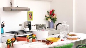 A modern kitchen with a white countertop, a stove, a sink, and a dining area with green chairs. - Aloha 2.0 Tropical Oasis in Wicker Park Sleeps 23 with Backyard Patio (Chicago)