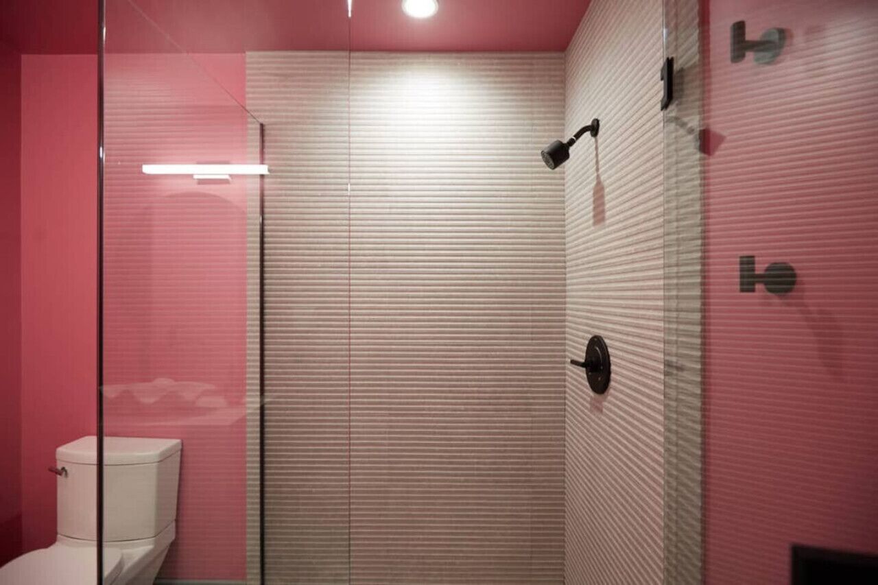 Un baño moderno con cabina de ducha de vidrio, inodoro y toallero de pared.