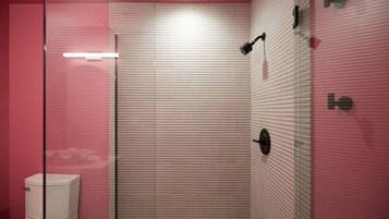 Un baño moderno con cabina de ducha de vidrio, inodoro y toallero de pared.