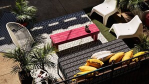 An outdoor seating area with a red table, white chairs, and patterned cushions. - Aloha 2.0 Tropical Oasis in Wicker Park Sleeps 23 with Backyard Patio (Chicago)